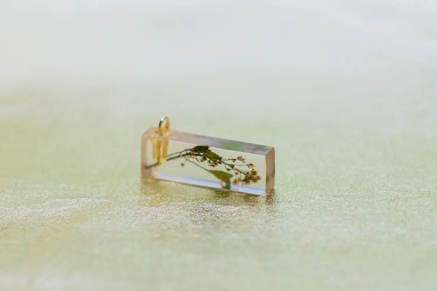 Small rectangular resin pendant, flowers & leaves inside.