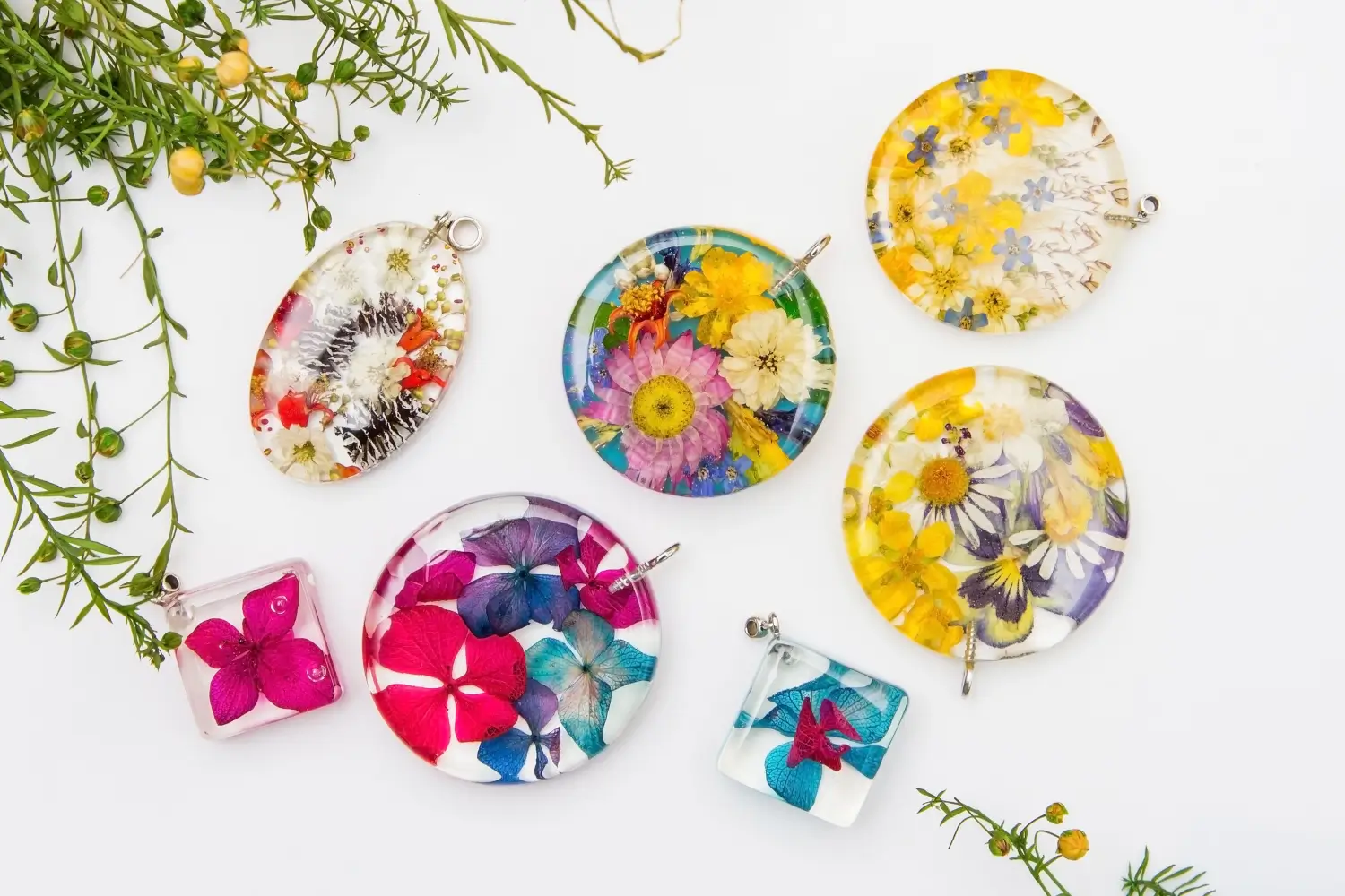 Assorted pressed flower pendants in resin.  Colorful floral designs.