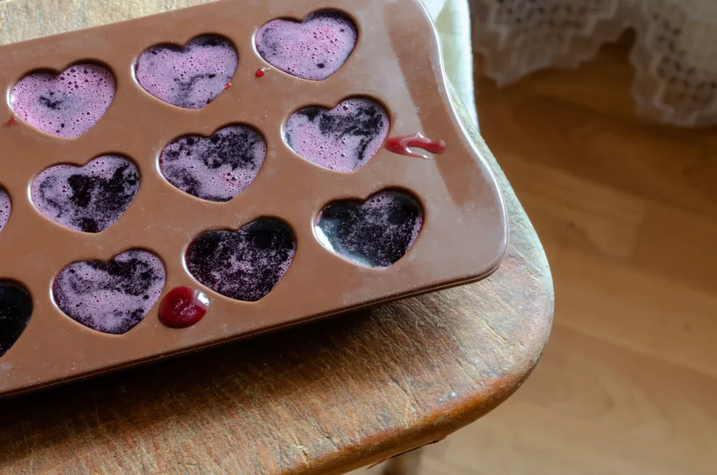 Heart-shaped silicone mold filled with purple liquid, likely for candy.