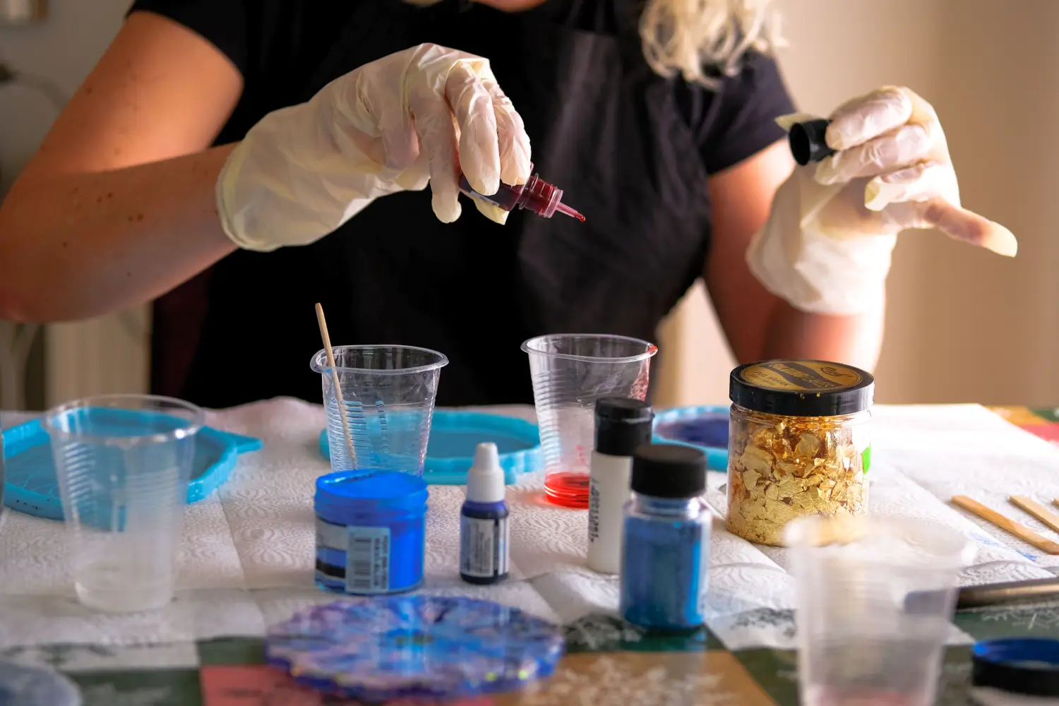 Person in gloves adding red dye to resin mixture.  Resin craft supplies.