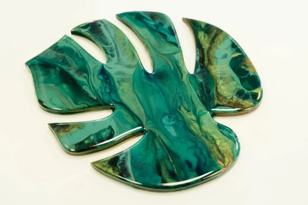 Resin-coated monstera leaf, teal and gold marbled design.